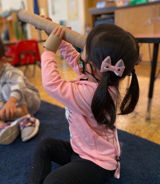 Child looking through a paper tube like a Telescope